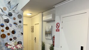 A hallway with a patterned floor, a black rug, a wall with circular mirrors, and a door with a number plate. - Hotel Galeón Boutique (Calpe)
