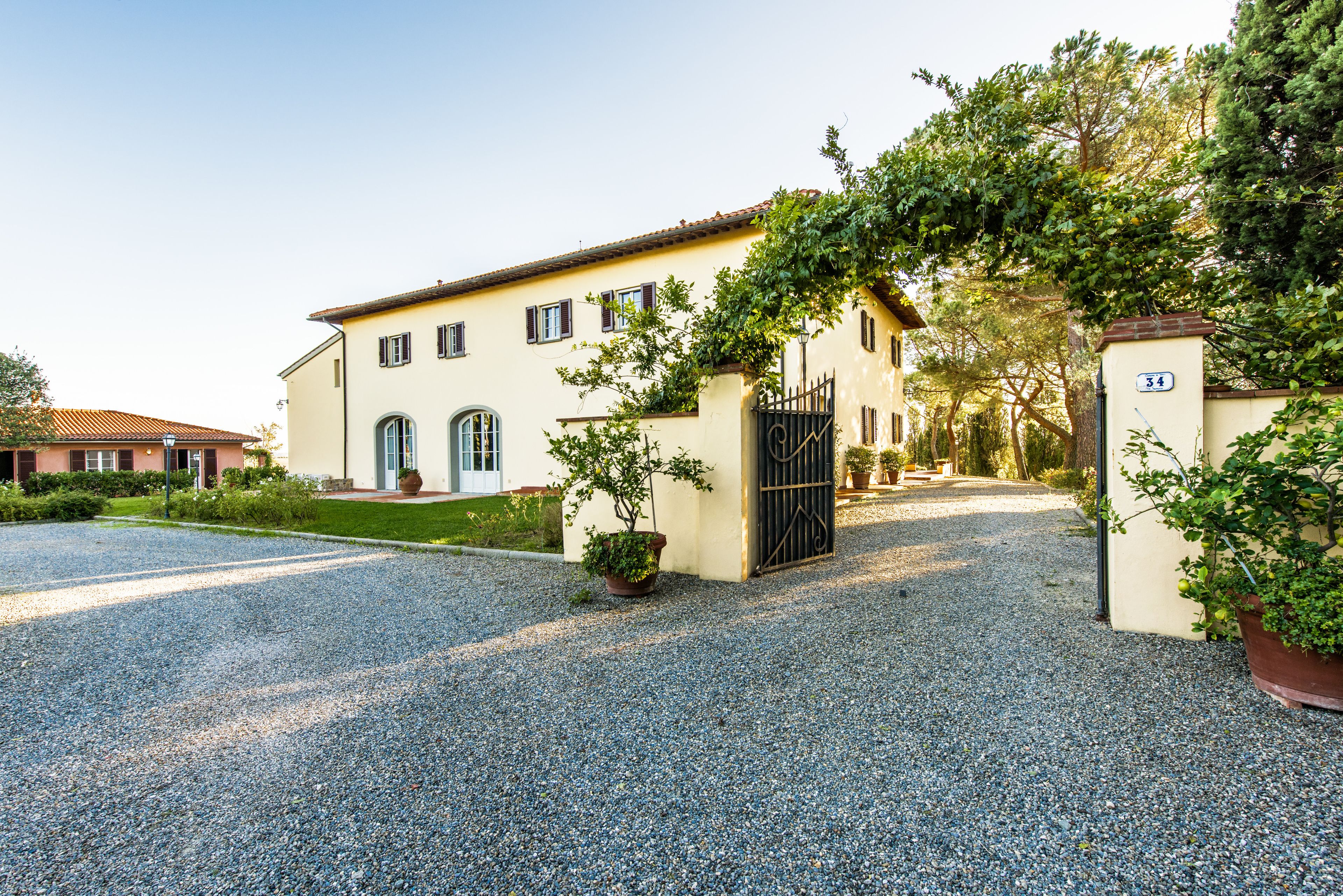 A large building with a gravel driveway and a black gate.