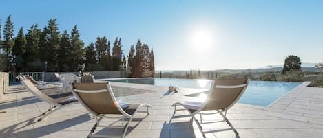 Een seizoensgebonden buitenzwembad, een infinitypool en ligstoelen