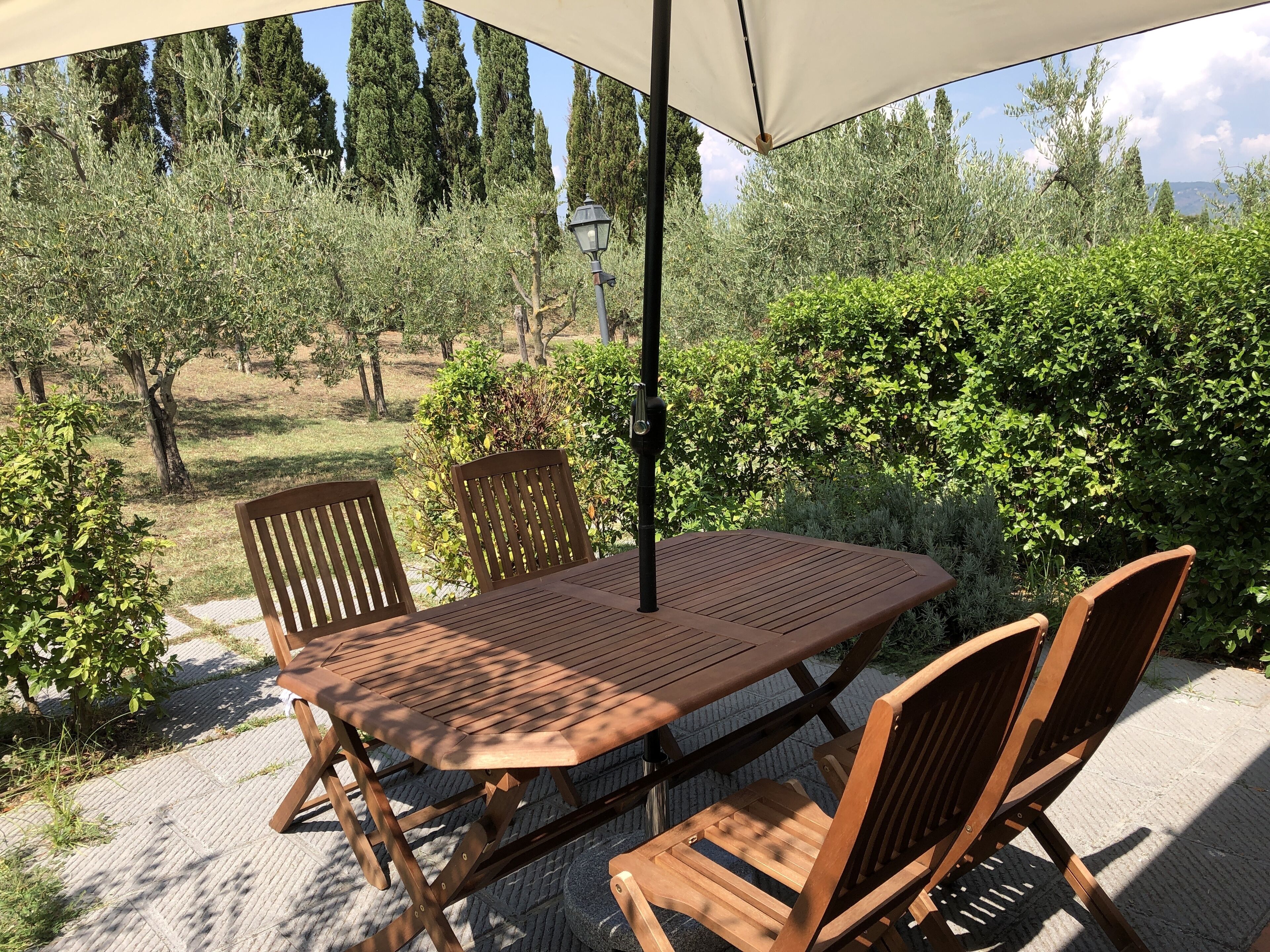 Eine Außenpatio mit Holztisch und -stühlen, einem Baldachin und einem Laternenpfahl.