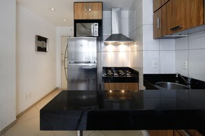 A modern kitchen with stainless steel appliances, a black countertop, and wooden cabinets. - Rio Rentals 021 - U010 Excelente apartamento em Copacabana (Rio de Janeiro)