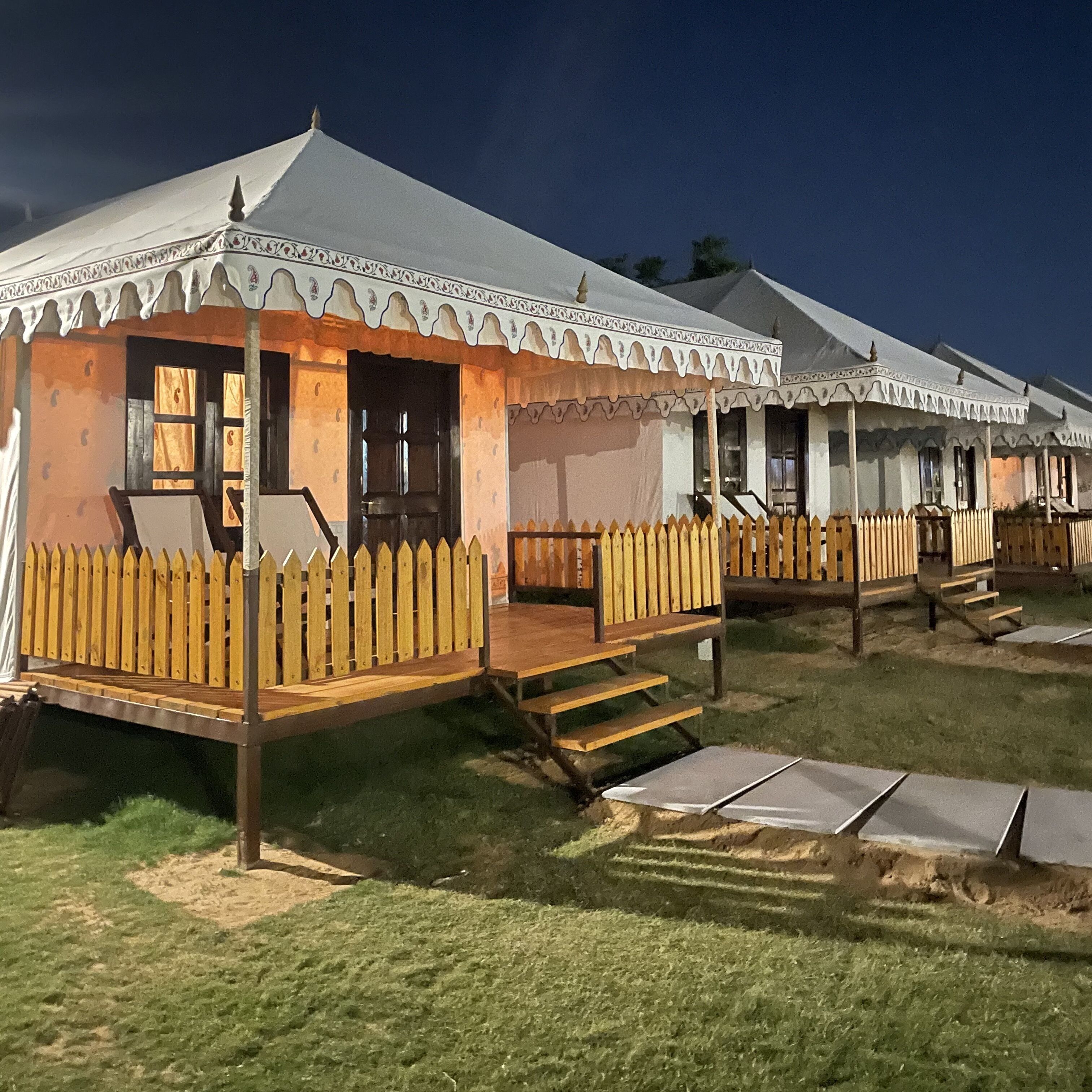 A row of tents with wooden decks and steps leading to the entrance.