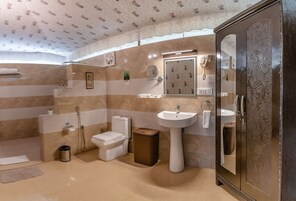 A bathroom with a toilet, sink, shower, and cabinet.