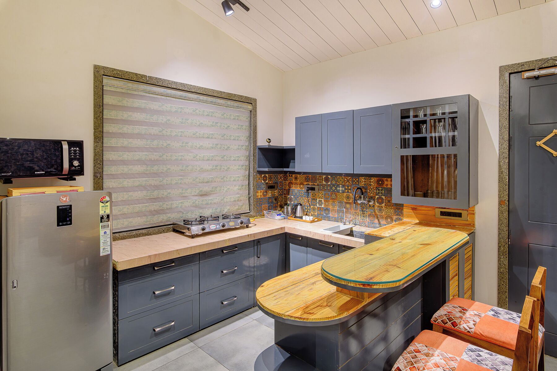 Una cocina compacta con estufa a gas integrada, un refrigerador y una isla de madera con asientos.