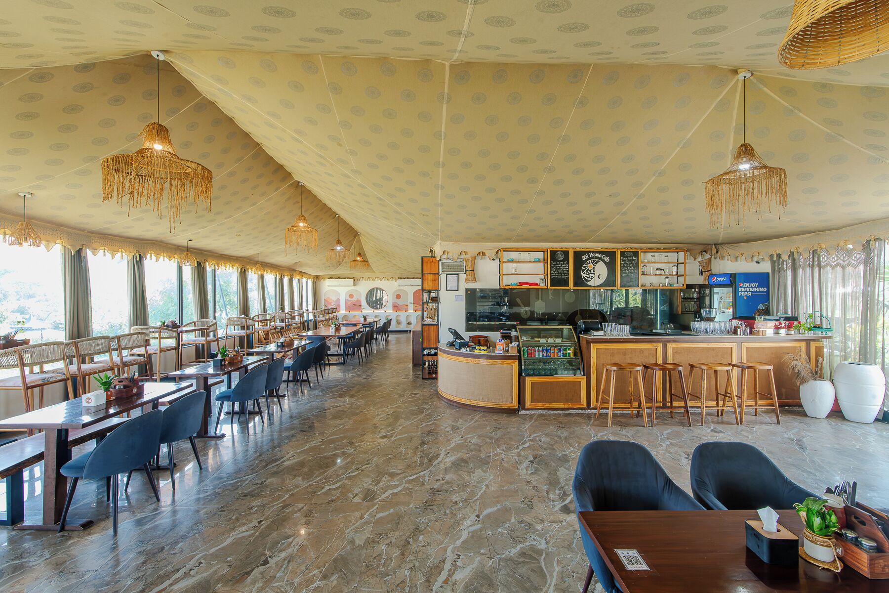 A spacious restaurant with a bar area, marble flooring, and hanging chandeliers.