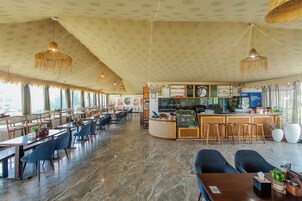 Un restaurante espacioso con zona de bar, suelo de mármol y candelabros colgantes.