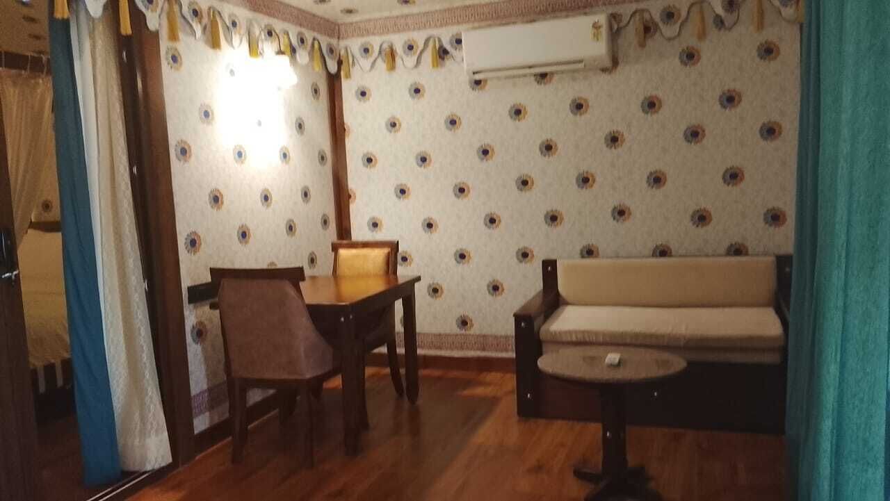 Et værelse med trægulv, et spisebord med stole, en sofa og et lille rundt bord.