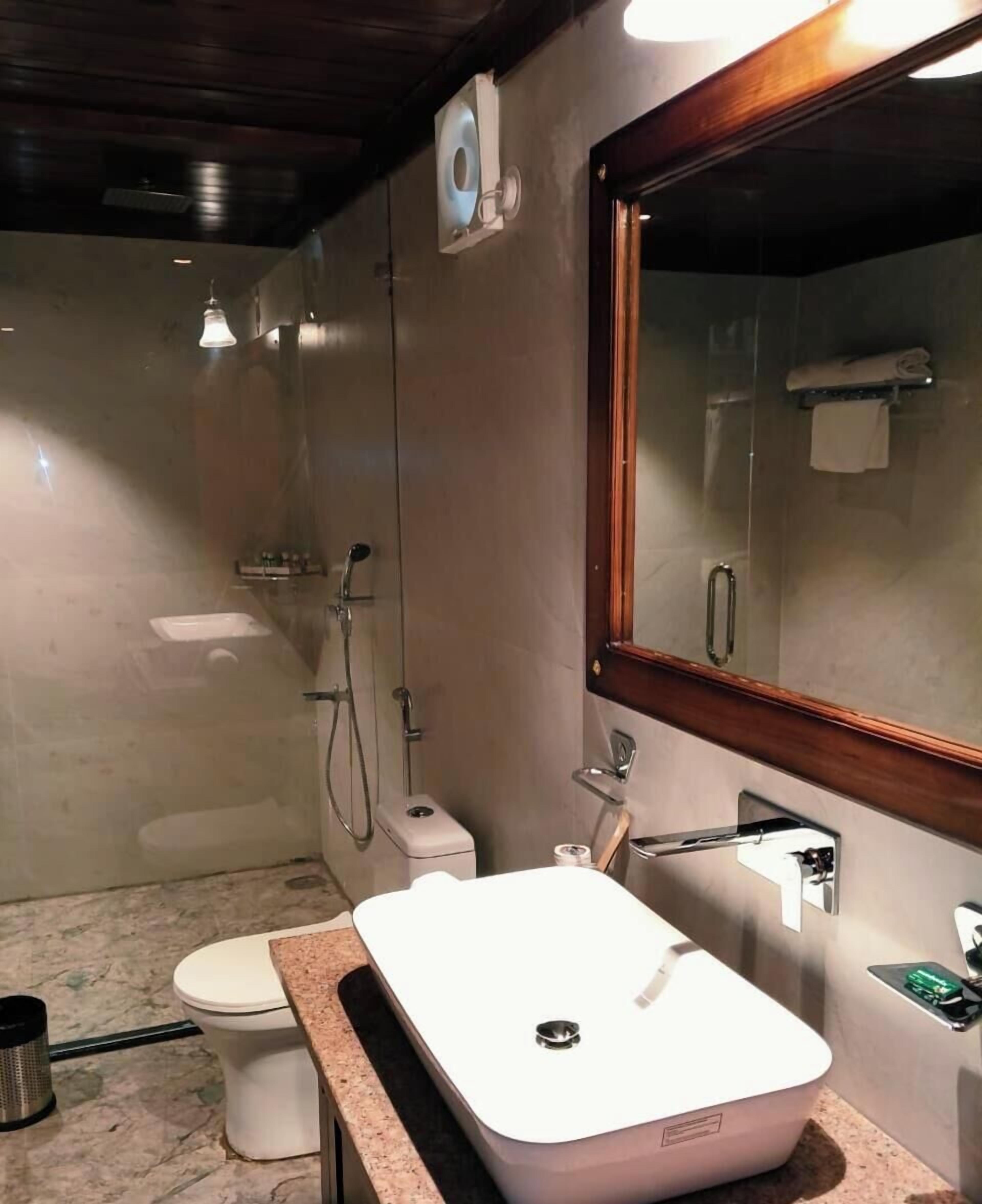Un baño con lavamanos blanco, inodoro, ducha y espejo.