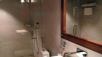 Un baño con lavamanos blanco, inodoro, ducha y espejo.