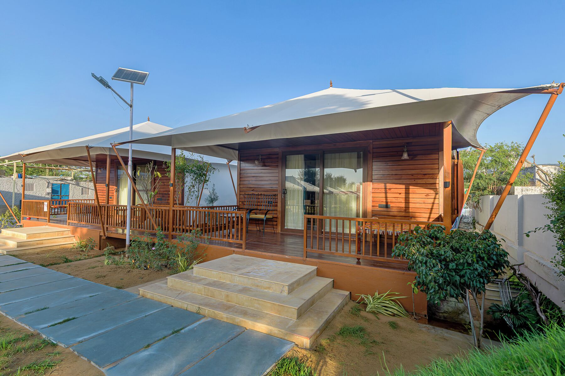 A wooden cabin with a covered porch, steps leading to the entrance, and a solar panel.
