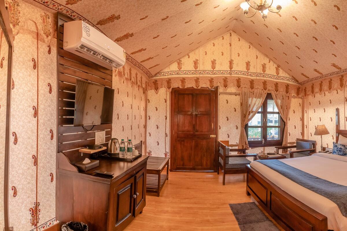 A bedroom with a large bed, a desk, a wardrobe, and a window.