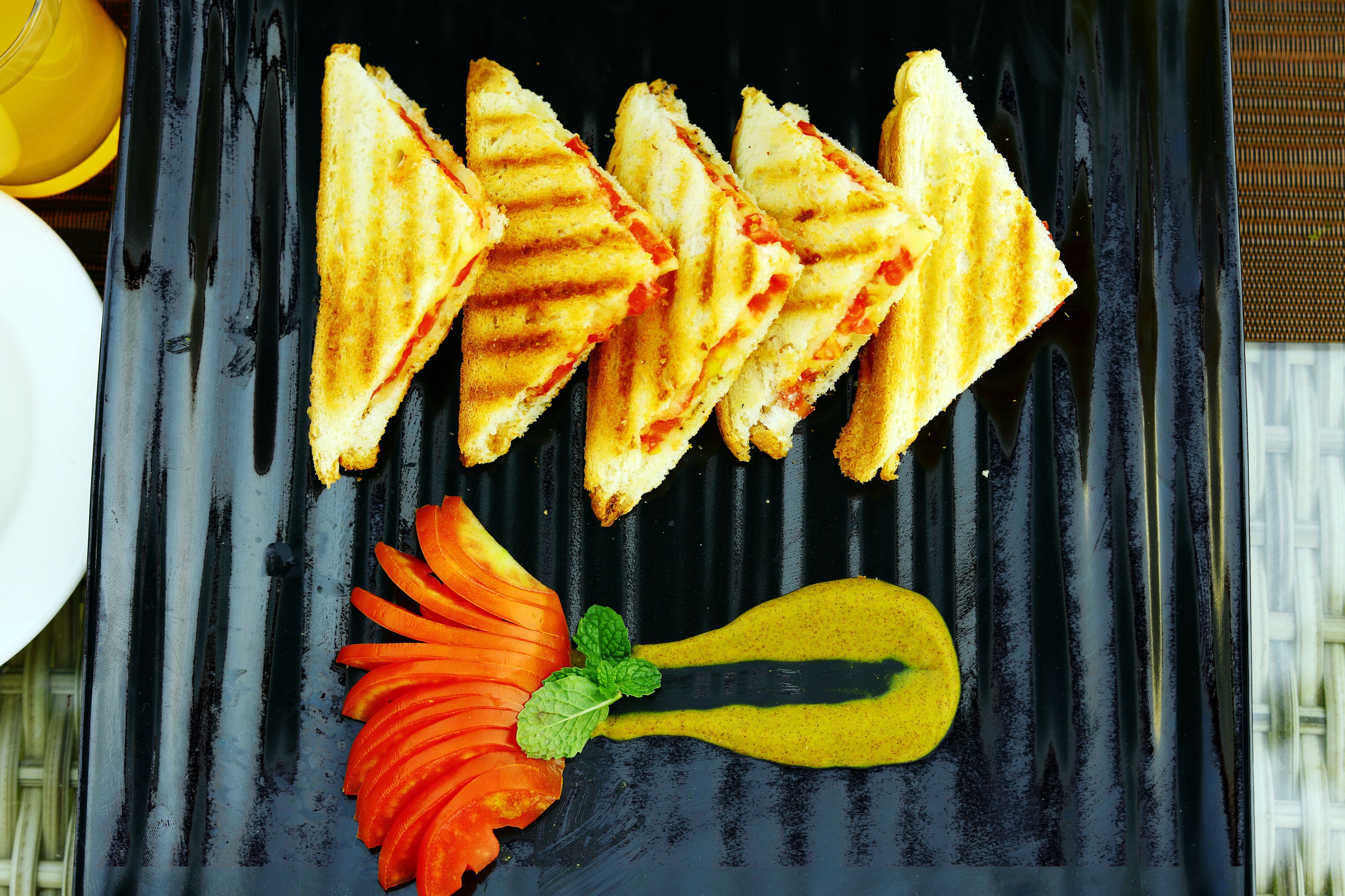 Un piatto nero con panini grigliati e una carota come guarnizione decorativa.