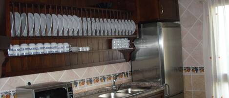 A kitchen with wooden cabinets, a stainless steel refrigerator, a microwave, and a sink.