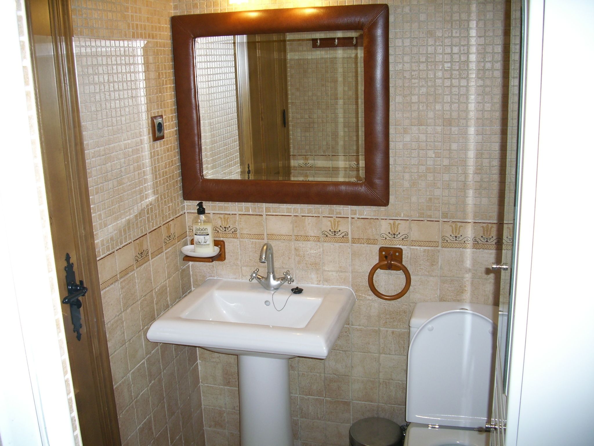 A bathroom with a white sink, a mirror, and a toilet.