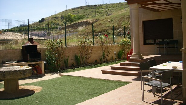 An outdoor patio with a grill, seating area, and a view of a hilly landscape. - Casa Rural Las Murallas (Brihuega)