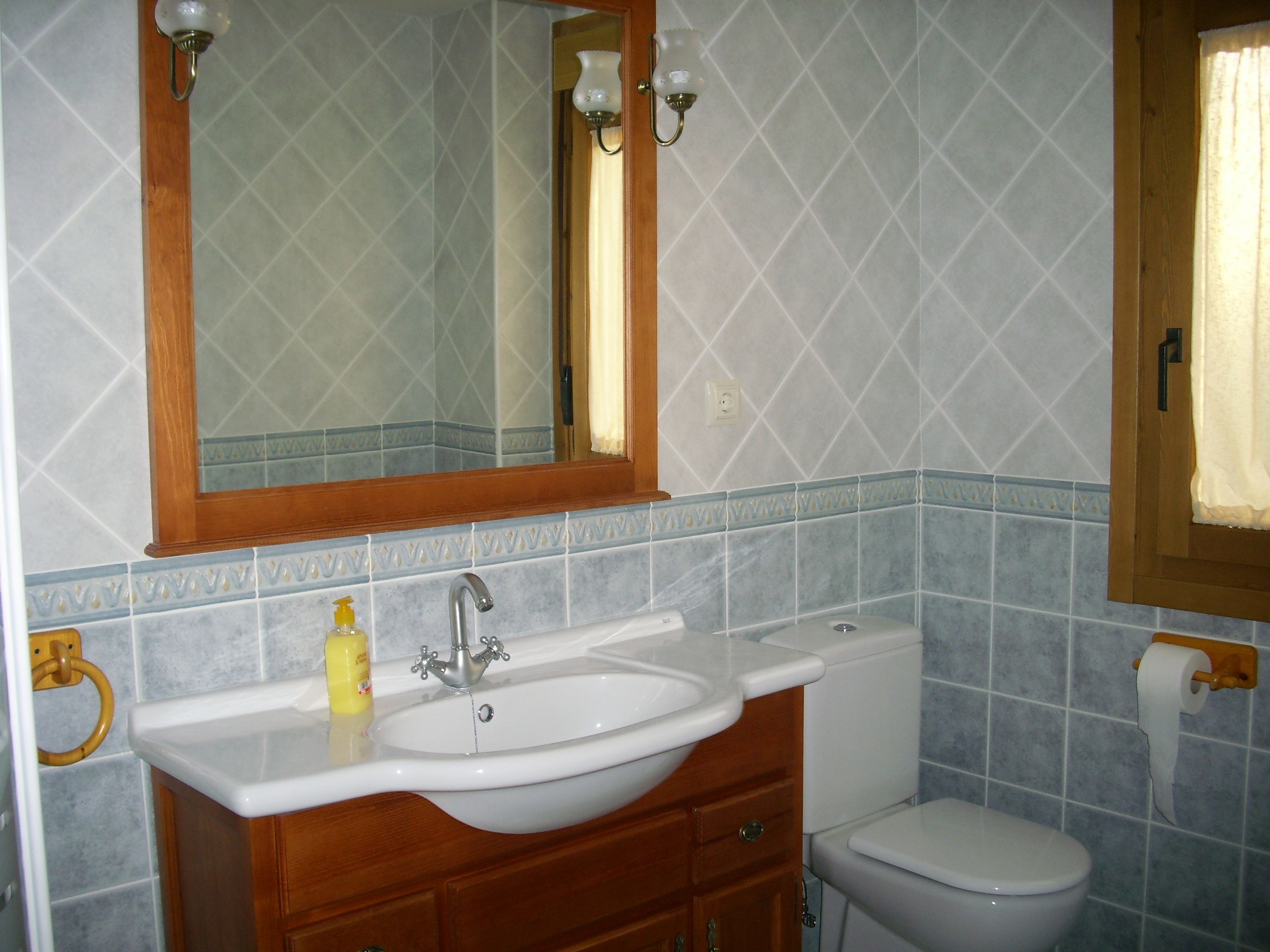 Een badkamer met een wit wastafel, houten wastafelmeubel en een spiegel erboven.