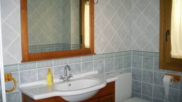 Een badkamer met een wit wastafel, houten wastafelmeubel en een spiegel erboven.