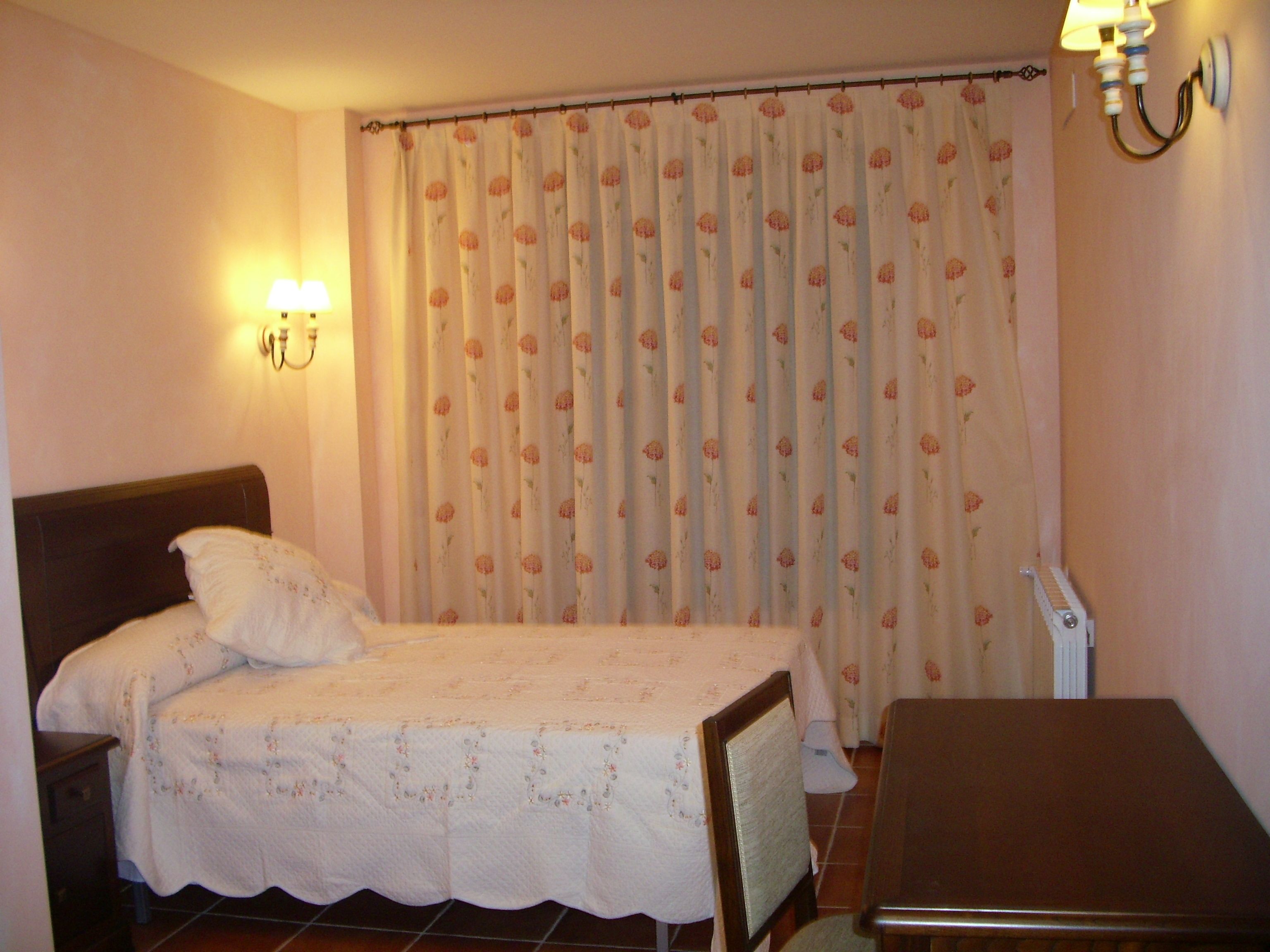A bedroom with a bed, a nightstand, a table, and a lamp.