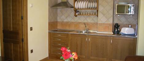 A kitchen with wooden cabinets, a microwave, a toaster, and a vase with flowers on a table.