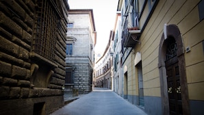 A narrow street flanked by historic stone buildings with arched windows and doors. - Dimora Dell'Erbe (Montepulciano)