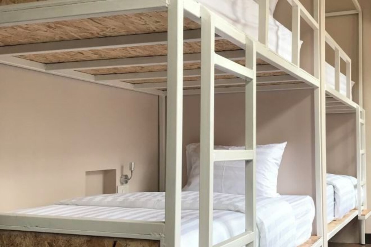 A bunk bed room with white bedding and a wooden ceiling.