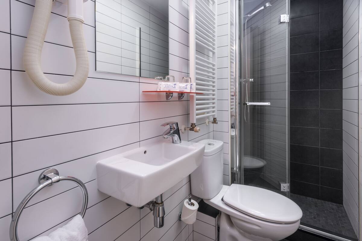A modern bathroom with a white sink, toilet, and a glass shower enclosure.