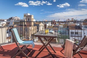 Una terraza en la azotea con una mesa, sillas y vistas a la ciudad.