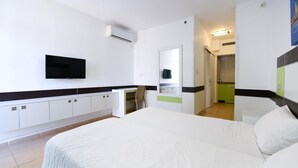 A hotel room with a large bed, a desk with a chair, a flat-screen TV mounted on the wall, and a bathroom visible through an open door. - HI Tel Aviv (Tel Aviv)