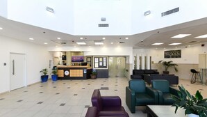 A spacious lobby with a reception desk, seating area, and a large window. - HI Tel Aviv (Tel Aviv)