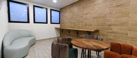 Uma sala de reuniões moderna com parede de tijolos de madeira, uma mesa redonda de madeira e várias cadeiras estofadas.