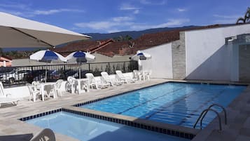 Una piscina al aire libre, sombrillas, sillones reclinables de piscina