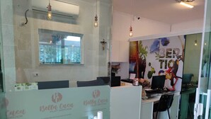 A reception area with a glass partition, a mounted air conditioner, and a window with a view of trees. - Bella Casa Flat Service (Bertioga)