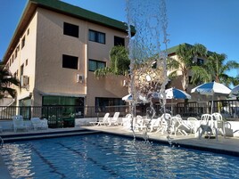 Una piscina al aire libre, sombrillas, sillones reclinables de piscina