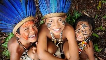 Three individuals wearing traditional attire with feathered headdresses and face paint.