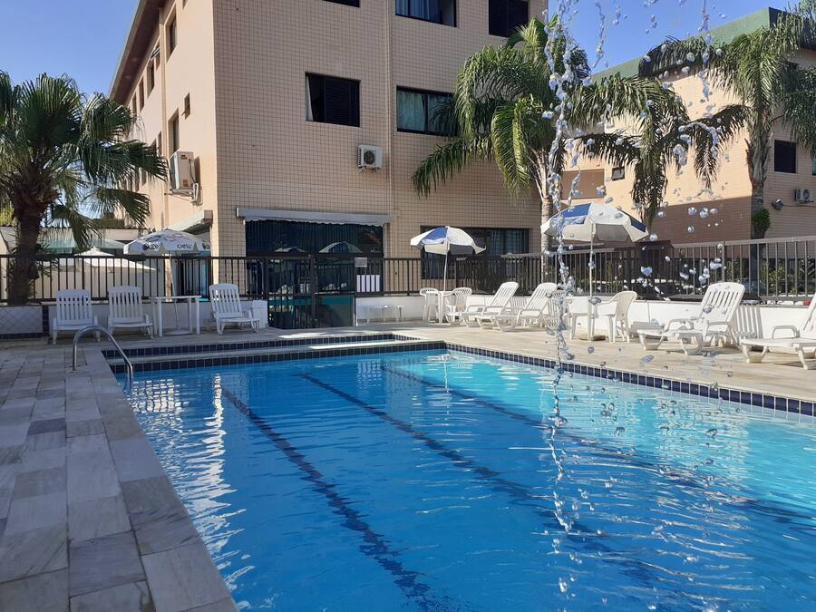 Una piscina al aire libre, sombrillas, sillones reclinables de piscina