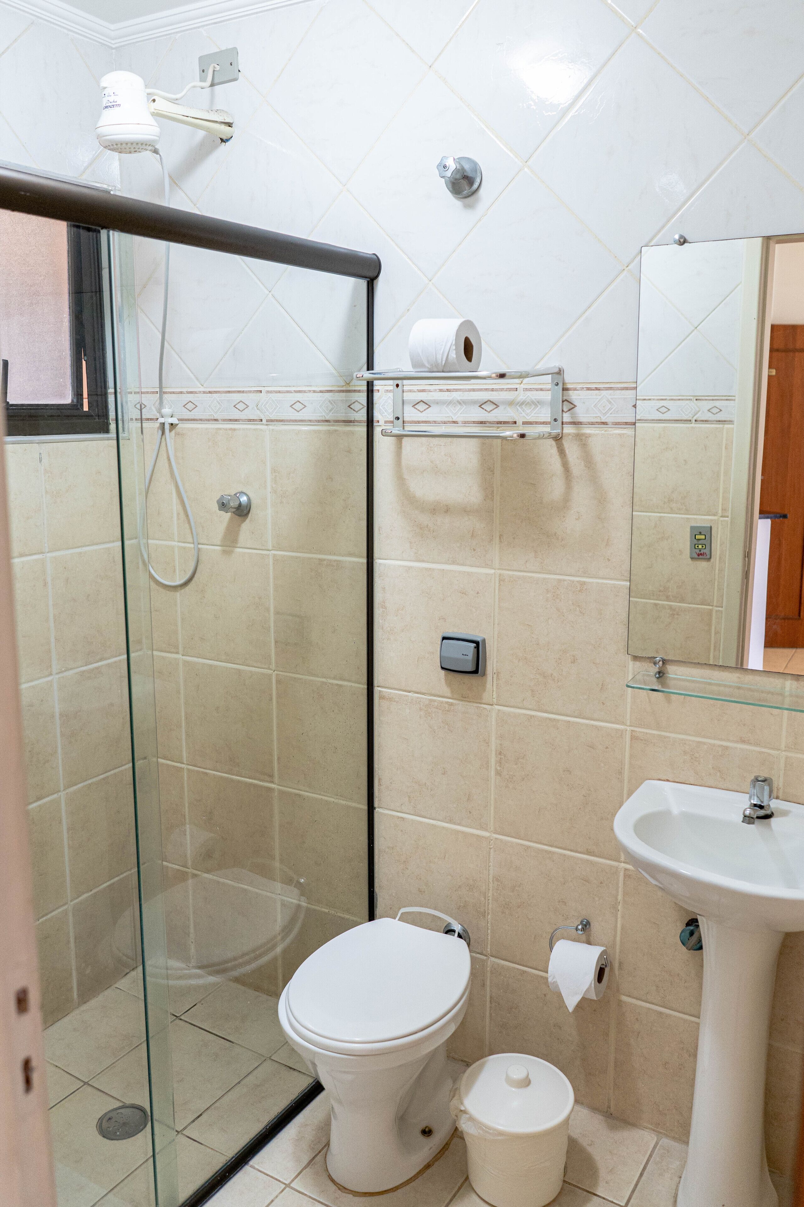 A bathroom with a glass-enclosed shower, a toilet, a sink, and a mirror.