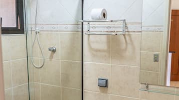 A bathroom with a glass-enclosed shower, a toilet, a sink, and a mirror.