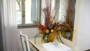 Ein Badezimmer mit einem weißen Waschbecken, einem Spiegel und einer Vase mit Blumen.