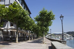 A waterfront promenade with outdoor seating, a bridge, and boats. - Hotel Boutique Bahía de Plentzia (Plencia)