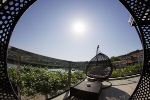 A balcony with a hanging chair, a view of a river, and a clear sky. - Hotel Boutique Bahía de Plentzia (Plencia)
