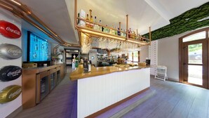 A bar area with a wooden counter, shelves with bottles, and a green textured wall. - Hotel Boutique Bahía de Plentzia (Plencia)