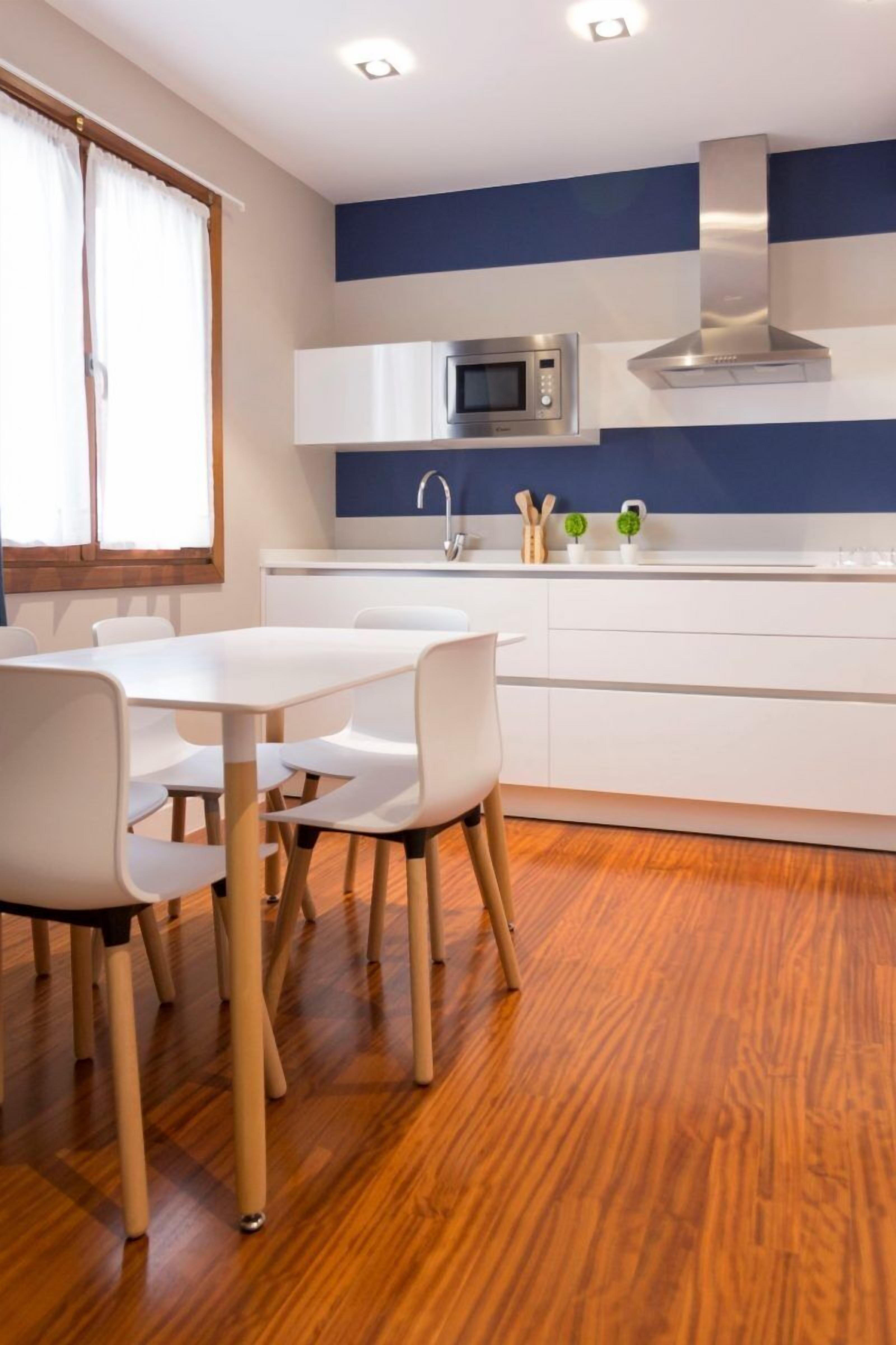 Una cocina moderna con armarios blancos, un microondas de acero inoxidable y una campana extractora empotrada.