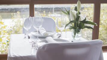 A table set for a meal with a view of a river and hills in the background.