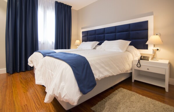 A hotel room with a large bed, two bedside tables, and a nightstand. - Hotel Boutique Bahía de Plentzia (Plencia)