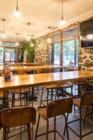 Un restaurante con una barra de madera larga, paredes de piedra y lámparas colgantes.