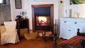 Une pièce chaleureuse avec une cheminée, une armoire blanche, une chaise et un lit.