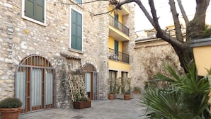 A courtyard with stone walls, potted plants, and a small tree. - Casa Portici (Torri del Benaco)