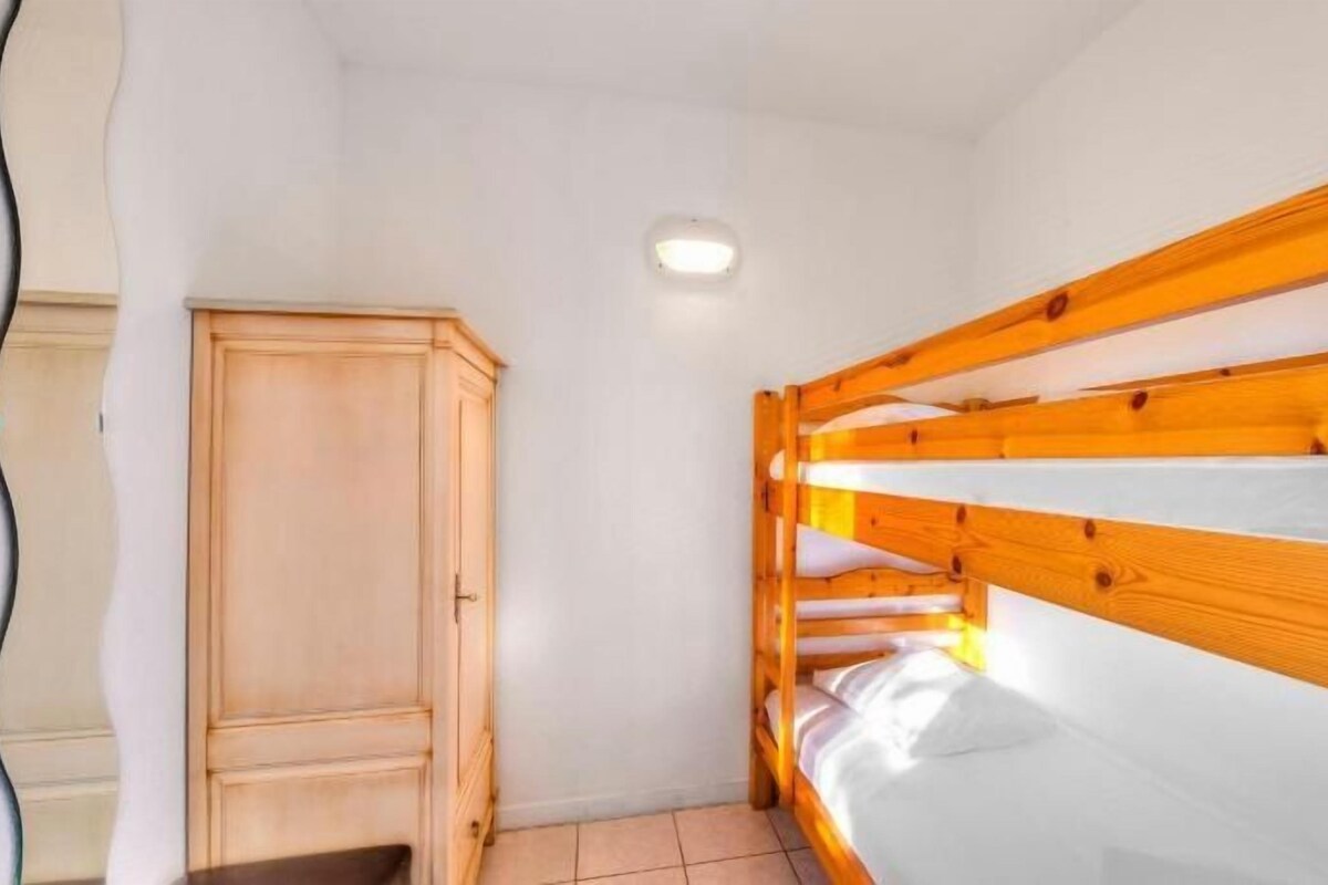 A bunk bed room with a wooden wardrobe and a ceiling light.
