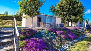 A small building with a door and windows, surrounded by a wooden fence and purple flowers. - Olydea Les Epesses (Les Epesses)