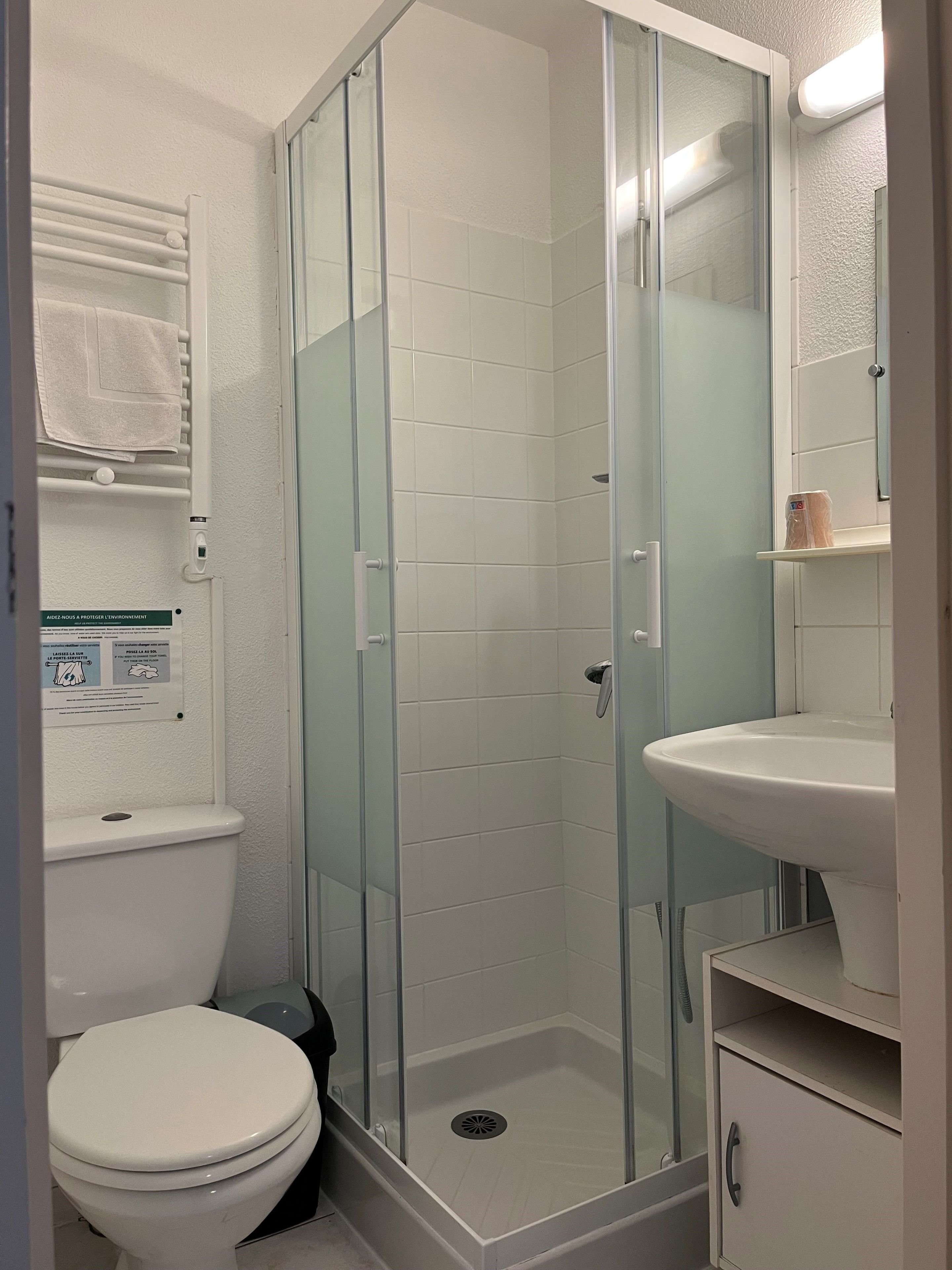 Un baño con ducha de vidrio, inodoro y lavabo.